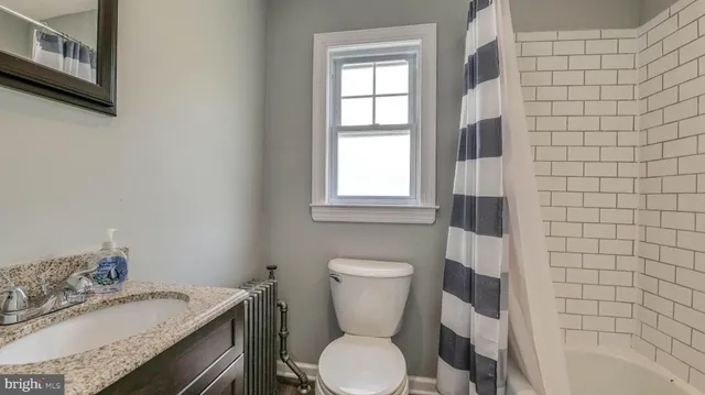 a bathroom with a granite countertop toilet sink and mirror
