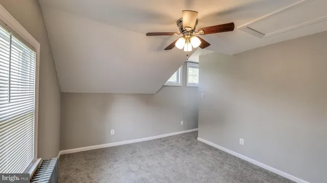 an empty room with a chandelier fan and windows