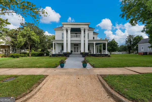 a front view of a house with a yard and potted plants
