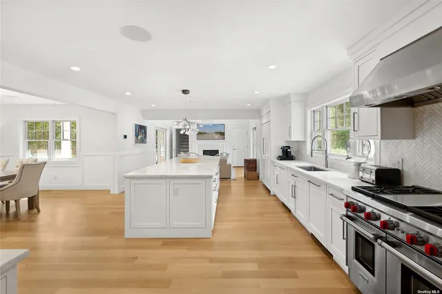 a large white kitchen with wooden floors and stainless steel appliances