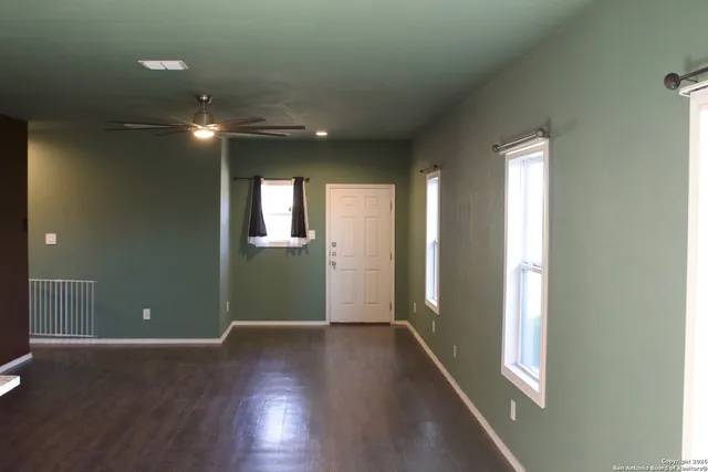 a view of a hallway with wooden floor and a kitchen