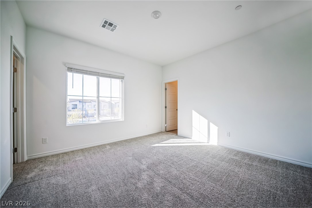 7348 North Decatur Boulevard, Unit 1 North Las Vegas, NV 89084 - Photo 5 of 17 A well-lit bedroom features plush carpeting and a large window providing ample natural illumination.