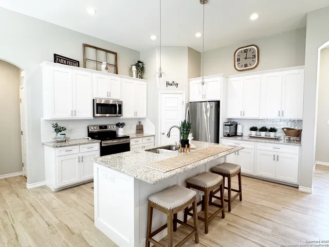 a kitchen with a refrigerator a stove a sink dishwasher with a dining table and chairs