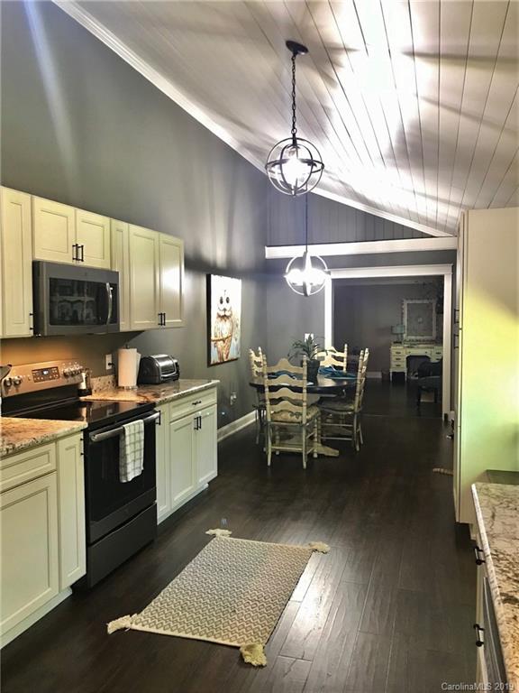 114 Riverview Road Tryon, NC 28782 - Photo 9 of 32 a kitchen with stainless steel appliances granite countertop a stove oven a sink dishwasher a dining table and chairs with wooden floor