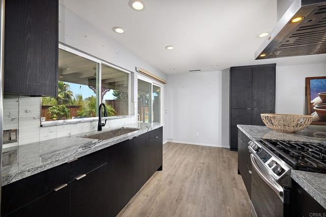 a kitchen with granite countertop a sink a counter space appliances and cabinets