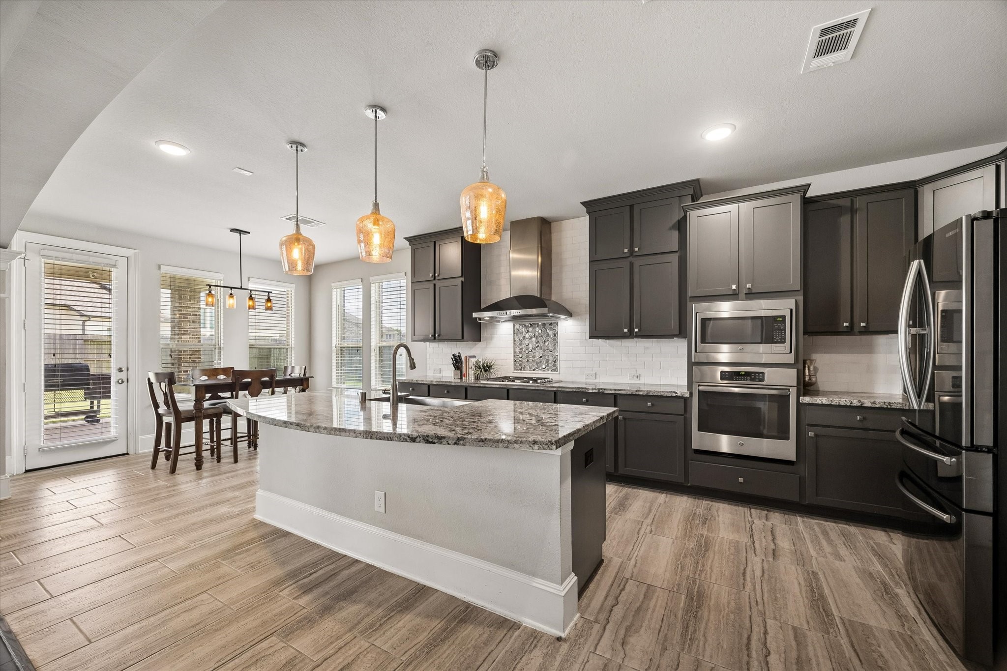 1907 Sapphire Pines Lane Rosenberg, TX 77469 - Photo 11 of 43 ABUNDANT CABINETRY WITH GRANITE COUNTERTOPS AND STAINLESS STEEL APPLIANCES MAKE THIS KITCHEN A TRUE TREAT TO COOK IN! DECORATIVE BACKSPLASH AND STAINLESS STEEL HOOD ANCHOR THE SPACE.