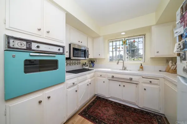 a kitchen with granite countertop white cabinets stainless steel appliances a sink and a window