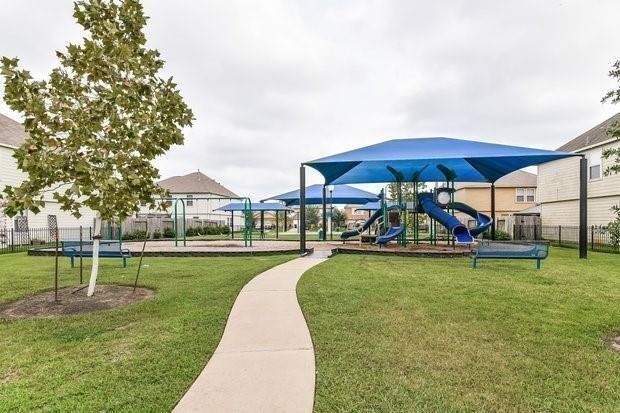 3235 Clipper Winds Way Houston, TX 77084 - Photo 17 of 26 a view of a swimming pool with a table and chairs under an umbrella