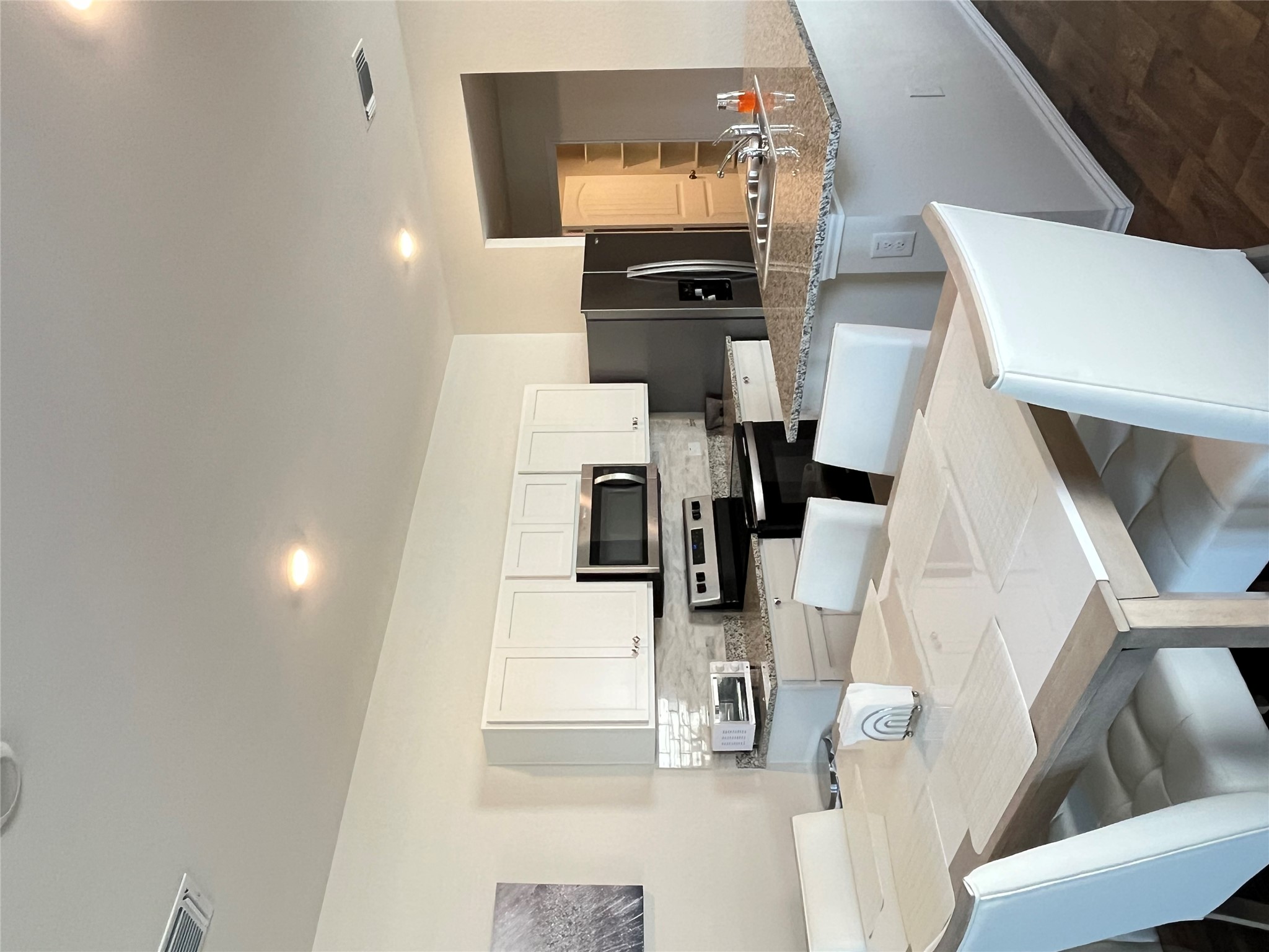12313 Token Trail Elgin, TX 78621 - Photo 8 of 15 Open-concept kitchen and dining area featuring white cabinetry, granite countertops, stainless steel appliances, a tiled backsplash, and recessed lighting