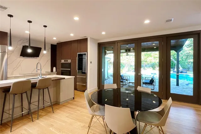 a kitchen with a table chairs sink and wooden floor