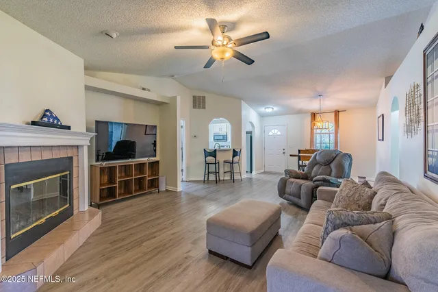 a living room with furniture a fireplace and a ceiling fan