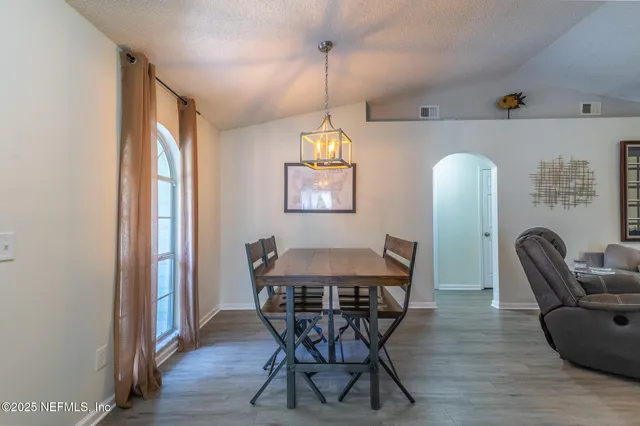 a dining room with furniture a chandelier and wooden floor