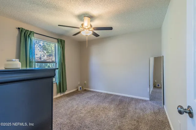 an empty room with windows and fan