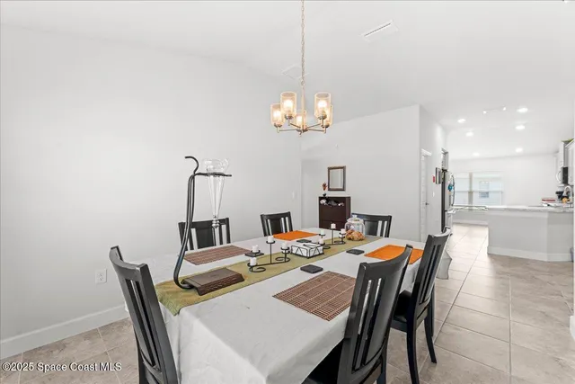a dining room with furniture a chandelier and kitchen view
