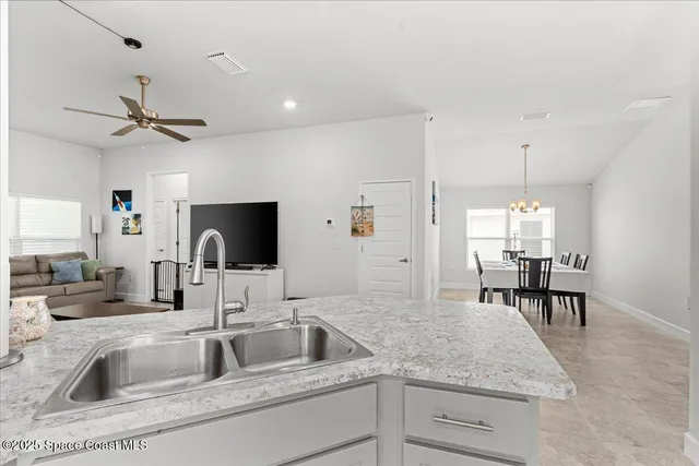 a kitchen with a sink a counter top space and living room view