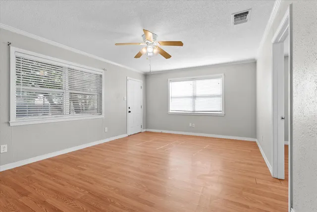 a view of empty room with wooden floor and fan