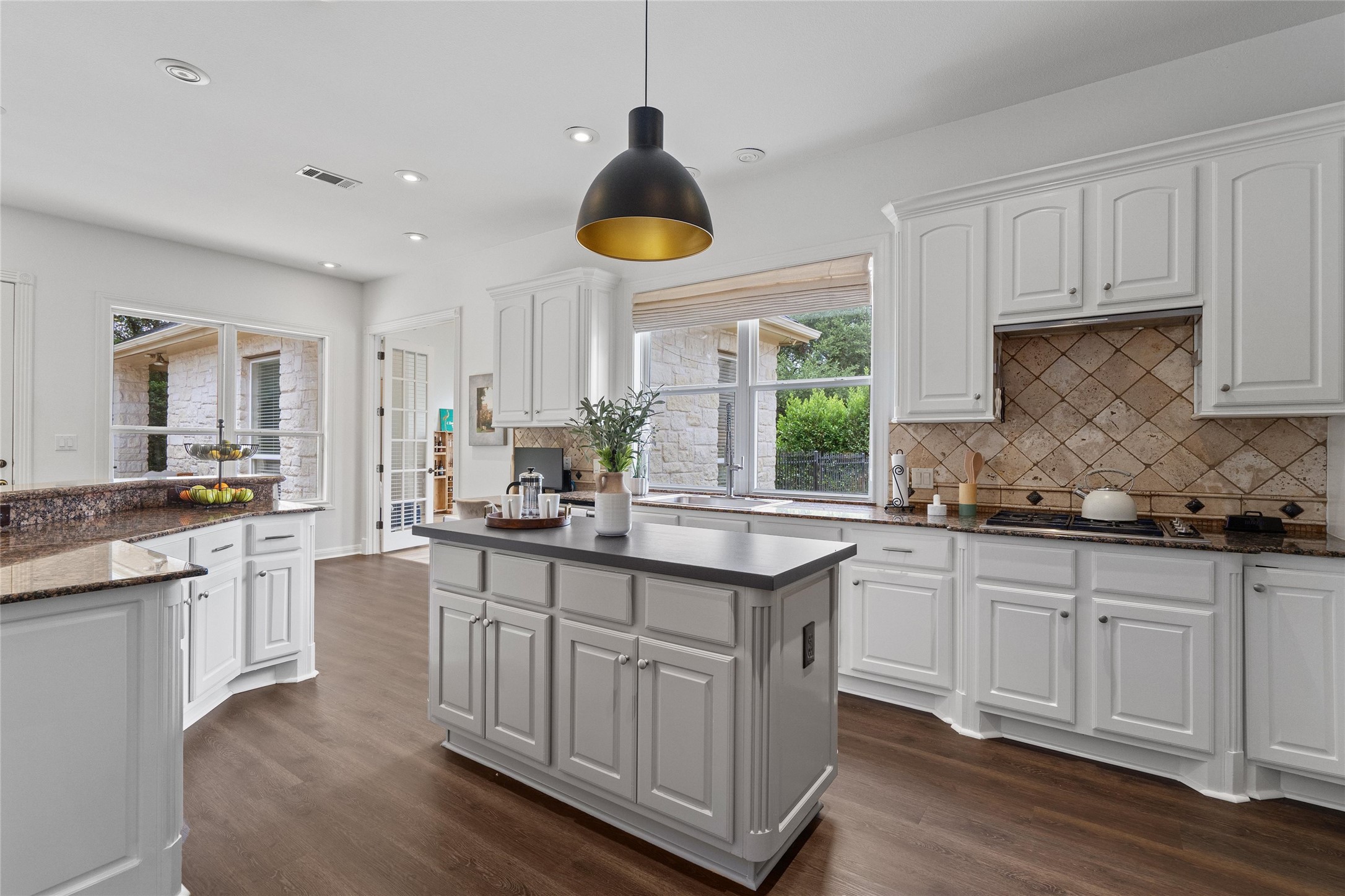 4313 Rio Robles Drive Austin, TX 78746 - Photo 12 of 40 A well-lit kitchen with warm wood flooring and elegant granite counters offers ample space for culinary creations.