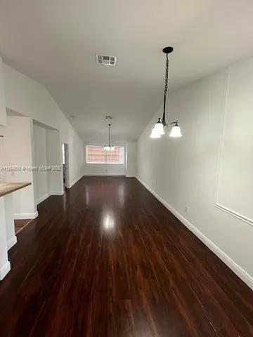a view of a room with wooden floor ceiling fan and kitchen appliances
