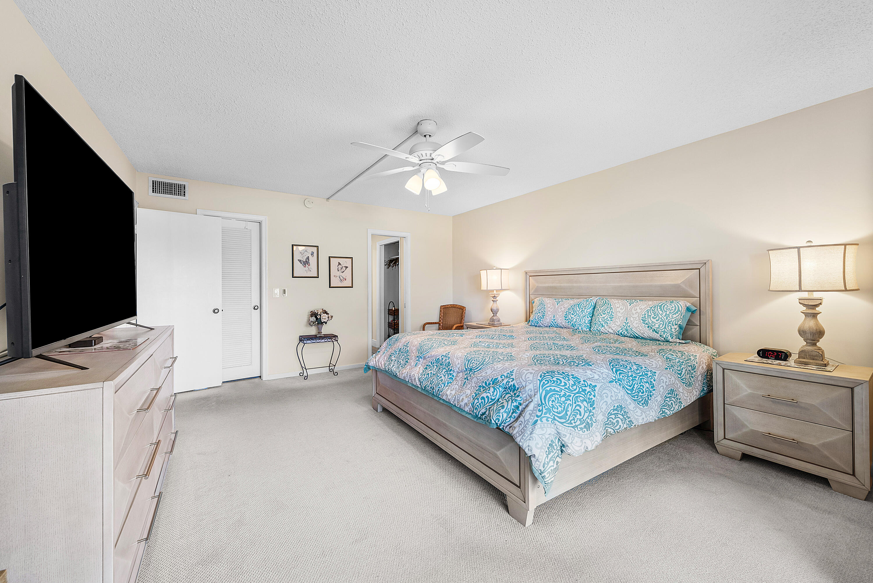 145 Atlantis Boulevard, Unit 203 Atlantis, FL 33462 - Photo 13 of 33 a spacious bedroom with a bed and a flat screen tv