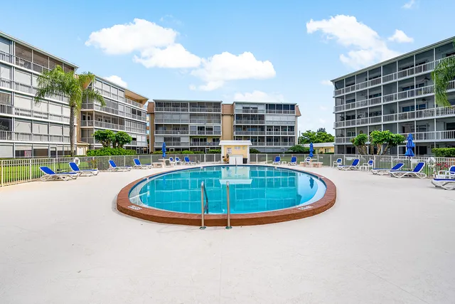 a swimming pool with outdoor seating and buildings in the back