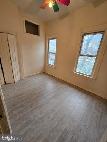 a view of an empty room with window and wooden floor