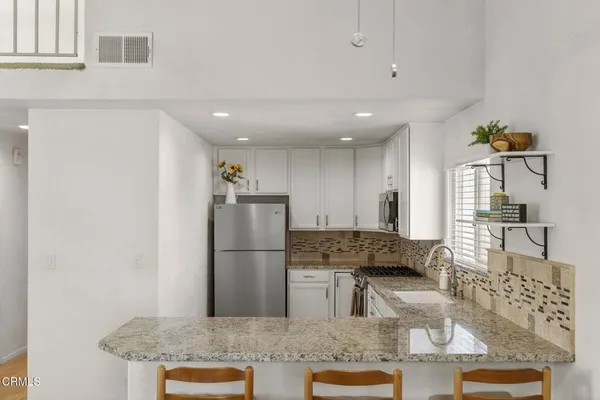 a kitchen with stainless steel appliances granite countertop a refrigerator and a stove