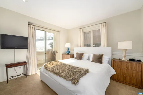 a bedroom with a large bed and a flat tv screen on dresser