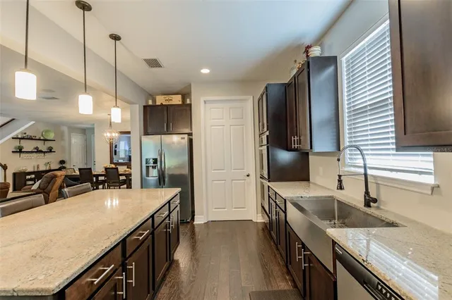 a kitchen with stainless steel appliances granite countertop a sink a stove and a refrigerator