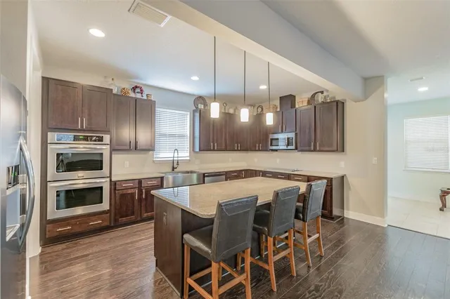 a kitchen with stainless steel appliances granite countertop a sink a stove and a wooden floors