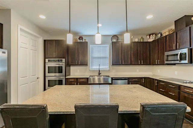 a kitchen with stainless steel appliances granite countertop a sink a stove and a refrigerator