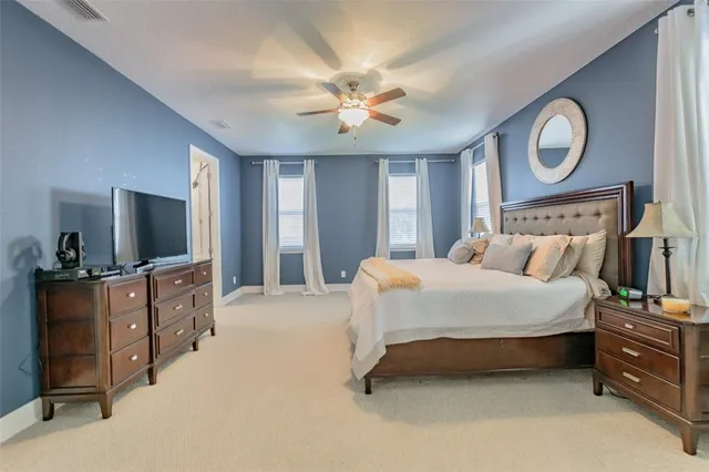 a spacious bedroom with a bed and a flat screen tv