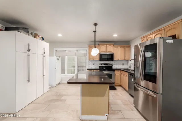 a kitchen with kitchen island granite countertop a refrigerator oven a sink dishwasher and white cabinets with wooden floor