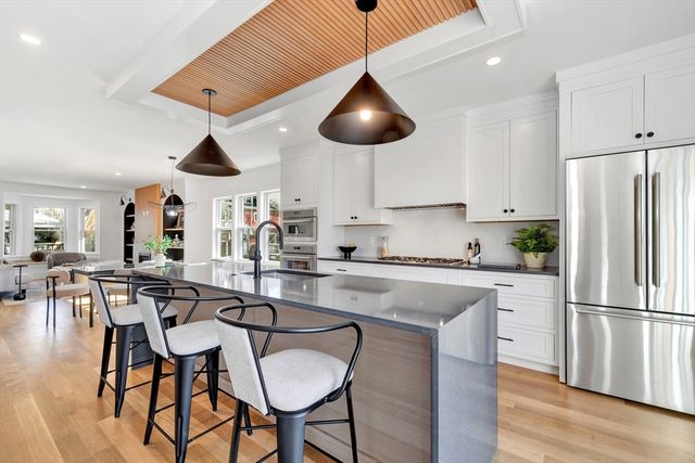 a kitchen with stainless steel appliances granite countertop a dining table chairs and white cabinets