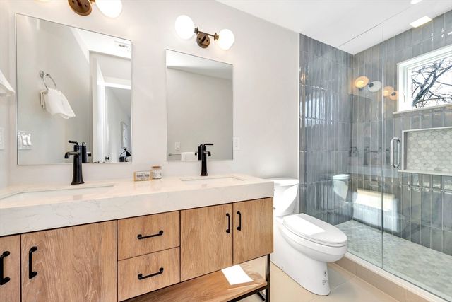 a bathroom with a granite countertop sink toilet mirror and shower