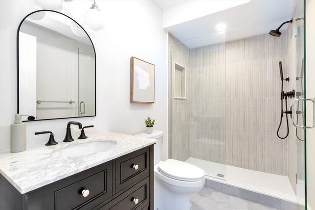 a bathroom with a granite countertop sink a toilet and shower