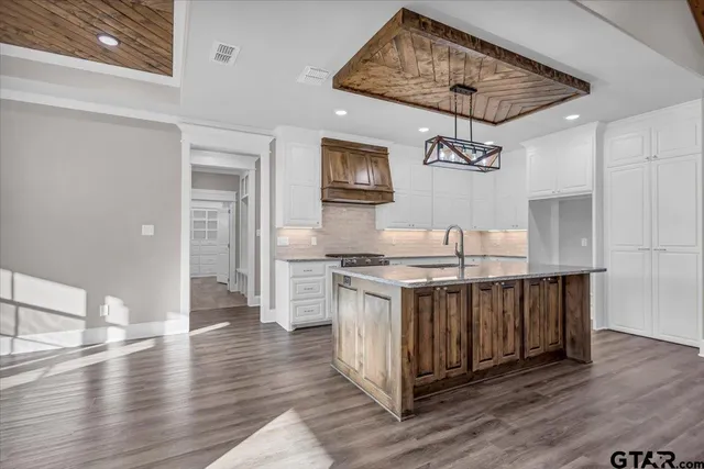 a kitchen with stainless steel appliances granite countertop a stove a sink dishwasher and a refrigerator with wooden floor