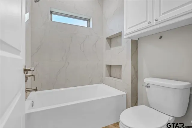 a white toilet sitting next to a bath tub