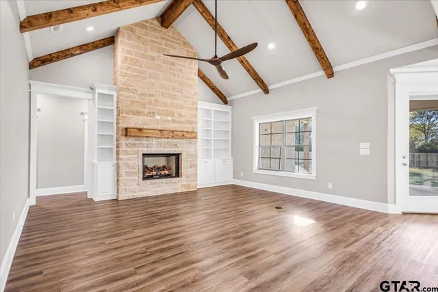 a view of an empty room with wooden floor fireplace and a window