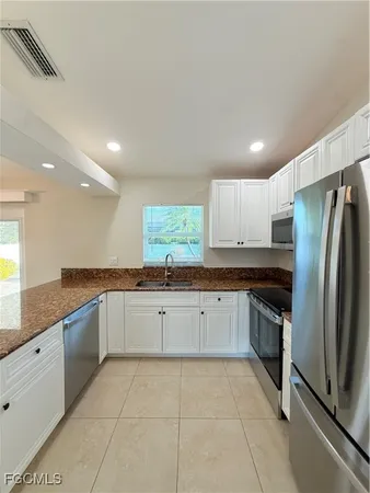 a large kitchen with stainless steel appliances lots of counter space and windows