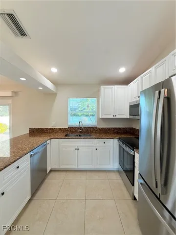 a large kitchen with stainless steel appliances lots of counter space and windows