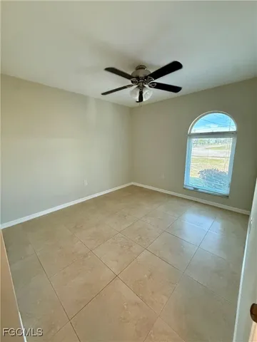 an empty room with windows and ceiling fan