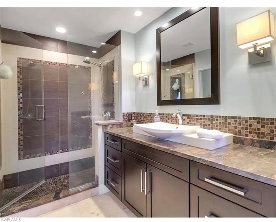 4650 Yacht Harbor Drive, Unit 125 Naples, FL 34112 - Photo 14 of 20 a bathroom with a granite countertop sink a mirror and a shower