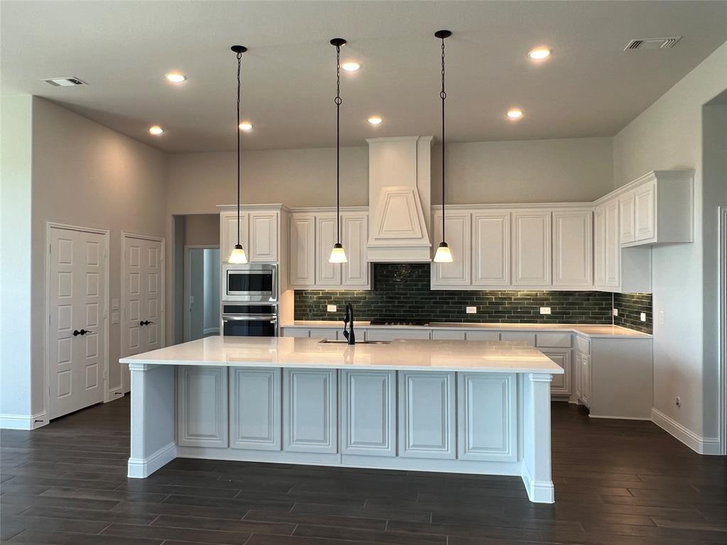 2108 Charters Circle Nevada, TX 75173 - Photo 11 of 37 Kitchen with white cabinets, decorative light fixtures, a large island with sink, dark wood-type flooring, and light stone counters