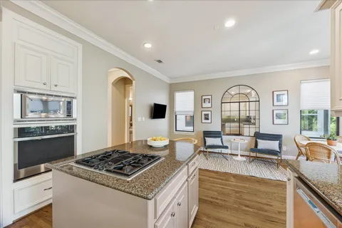 a kitchen with stainless steel appliances granite countertop a stove and a view of living room