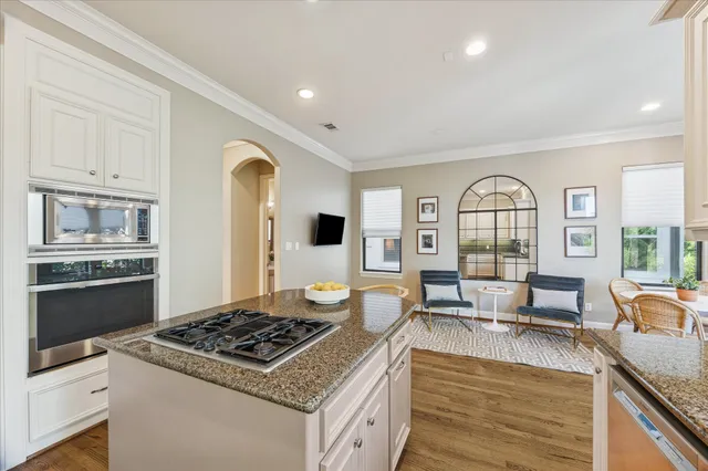 a kitchen with stainless steel appliances granite countertop a stove and a view of living room