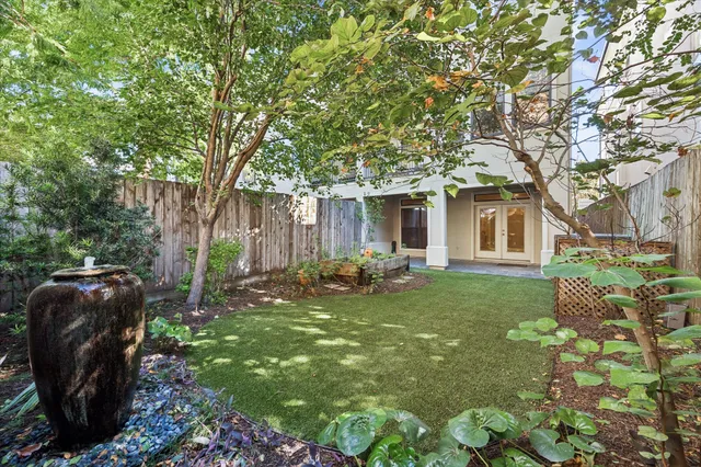 a view of a backyard with table and chairs potted plants and large tree