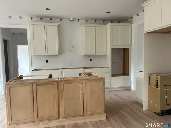 a kitchen with stainless steel appliances granite countertop a stove a sink a refrigerator and a dining table with wooden floor