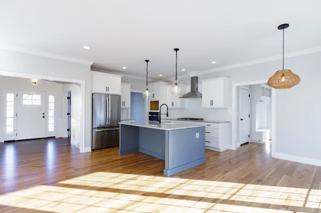 a kitchen with stainless steel appliances kitchen island granite countertop a refrigerator a sink a oven and a wooden floors