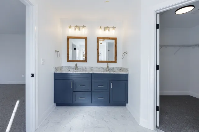 a bathroom with a granite countertop double vanity sink and a mirror
