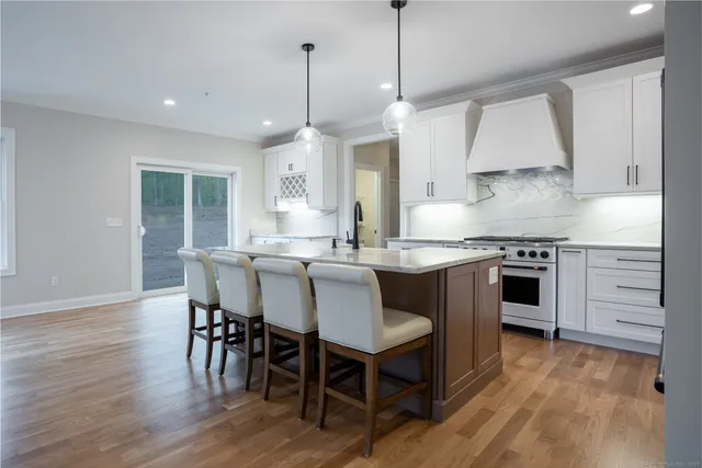 a kitchen with stainless steel appliances granite countertop a stove a sink a microwave a dining table and chairs